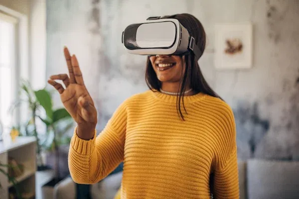 Woman wearing yellow uses VR headset at home.